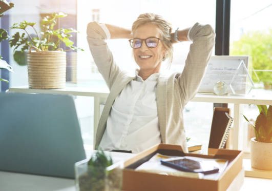 convien Business woman feeling accomplished and enjoying a break to stretch with hands behind her head in an office. Happy mature entrepreneur satisfied and relieved to have completed her deadlines and tasks