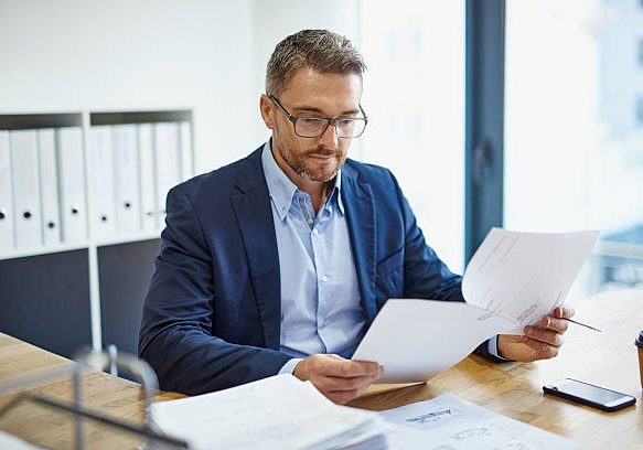 Shot of a mature businessman reading a document at his desk in an office Shot of a mature businessman reading a document at his desk in an office