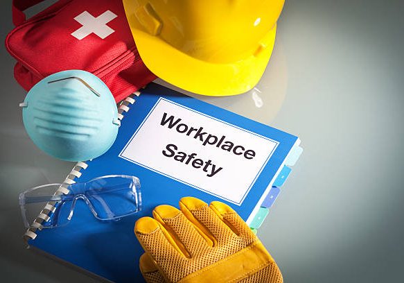 work safety Workplace safety handbook with occupational safety equipment still life, a work training class and instruction manual for using safety equipment and administering first aid. Employment education document with protective eyewear, hard hat, first aid kit, work glove, and pollution mask. Guidance and planning tools in horizontal format with copy space.